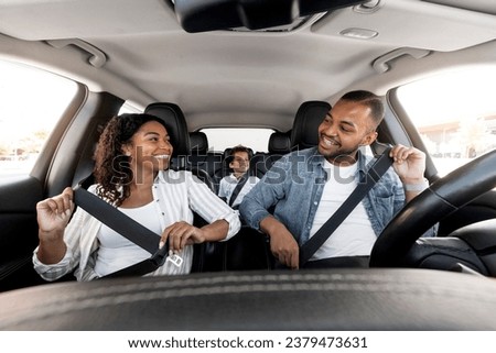 Safe Ride. Happy african american family young parents and son enjoying car journey together. Black mother looking at father while fasten seatbelt, getting ready for trip, family weekend