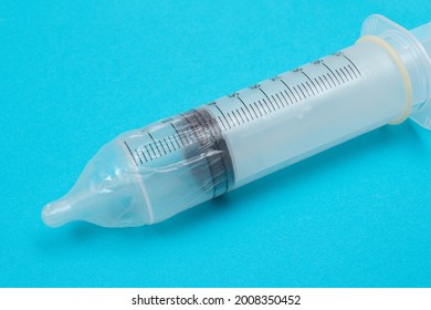 Safe Vaccine, Anti Vaccination Concept - Syringe in a Condom Lay on Blue Table in Clinic or Hospital. Mistrust of Vaccination. Natural Immunity. Skepticism About the Vaccine. Freedom and Human Rights