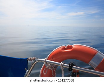 Safe Water Support Aid Circle. Rescue Red Lifebuoy Life Preserver Saver Ring On Sailboat And Blue Sky Baltic Sea.