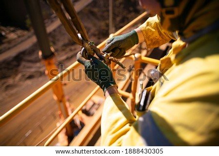 Safe work practices top view of rigger crane high risk worker wearing a safety glove fastening pin into D- shackle 4.5 ton lifting lug together with lift sling safety tagline prior load being lifted 