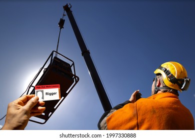 Safe workplace clear image of rigger licence card with trained rigger conducting positive communication on 2 way radio with crane operator during lifting operation at the background   - Powered by Shutterstock