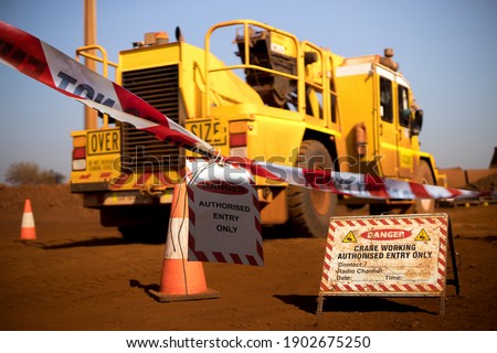 Safe workplace practice red and white warning danger tag tape sign applying taping off working area dropped object with crane lifting high risk work exclusion dropped zone construction site background