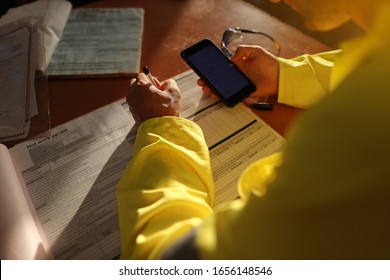 Safe Workplace Top View Of Construction Worker Setting On The Chair Holding Cell Phone And  Writing Emergency Site Phone Number On  Hot Work Permit Paperwork Prior Commence Work Of Each Task