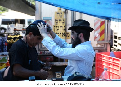 SAFED, ISRAEL - JUNE 6, 2018: An Unidentified Lubavitcher Hasidic Jew Puts Tefillin On An Unidentified Jewish Man In The Local Open Market In Safed, Israel