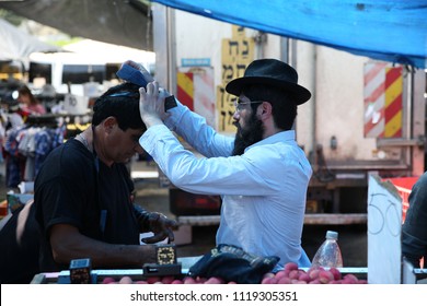 SAFED, ISRAEL - JUNE 6, 2018: An Unidentified Lubavitcher Hasidic Jew Puts Tefillin On An Unidentified Jewish Man In The Local Open Market In Safed, Israel