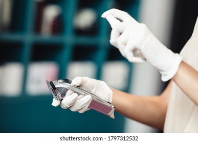 Safety at barber shop. Master disinfecting trimmer after work, close up - Powered by Shutterstock