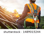 [safety body construction] Working at height equipment. Fall arrestor device for worker with hooks for safety body harness on selective focus. Worker as in construction background.