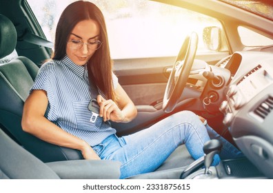 Safety and car driving concept. Close up photo of smiling young woman driver while she fastening seat belt.