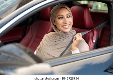 Safety Concept. Smiling Middle East Woman In Hijab Fastening Seatbelt, Driving In The City. Young Lady Sitting In Her Luxury Automobile, Following Safe Ride Rules, Ready For A Trip - Powered by Shutterstock