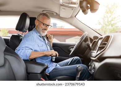 Safety driving concept. Handsome senior man driver fasten seat belt in car. Positive elderly gentleman sitting inside nice automobile, going to market, travelling alone, side view - Powered by Shutterstock