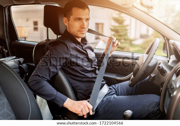 Safety driving concept. A man fastens his seat\
belt. Before driving
