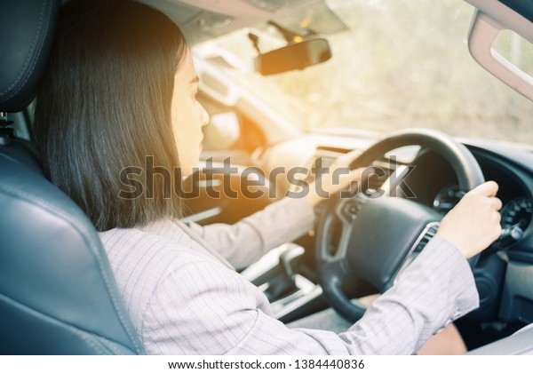 Safety driving concept, Smiling happy young  Chinese\
Thai Asian businesswoman driving a car in town, Confident and\
beautiful girl. Rear view  woman in business suit wear looking over\
her shoulder  