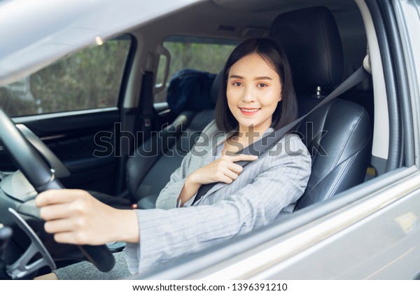 Safety driving concept, Smiling happy young  Chinese
Thai Asian businesswoman driving a car in town, Confident and
beautiful girl. Rear view  woman in business suit wear looking over
her shoulder  