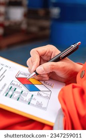 A safety engineer is using pen to rating the health risk assessment level of chemical hazardous material in the paperwork form. Industrial safety working scene, close-up and selecitve focus.