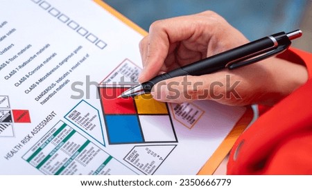 A safety engineer is using pen to rating the health risk assessment level of chemical hazardous material in the paperwork form. Industrial safety working scene, close-up and selecitve focus.