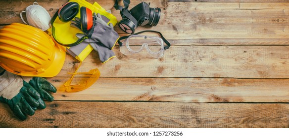 Safety equipment at work, constuction site. Protective hard hat, headphones, gloves and glasses on wooden background, banner, copy space, top view - Shutterstock ID 1257273256