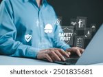 Safety First Concept. Work safety, Man typing on laptop with digital icons related to safety, protection, and regulations, including a hard hat, shield, and checklist, representing workplace safety.