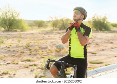 Safety first. Latin young man putting on a helmet and sunglasses to start road cycling. Fit cyclist preparing to start biking - Powered by Shutterstock