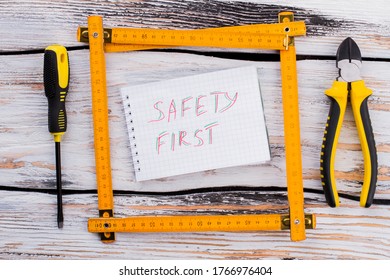 Safety first note in a frame made of an angle ruler. Top view flat lay.