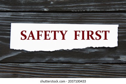 SAFETY FIRST - Words On A Torn Piece Of Paper On A Black Wooden Background. Info Concept