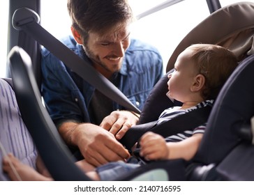 Safety First. A Young Father Strapping His Baby Into A Car Seat.