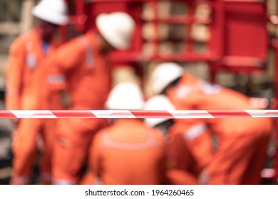 Safety Flag Line For Barricade Restricted Working Area With Blurred Background Of Worker Crowd Is Investigating Something. Close-up And Selective Focus At Flag Line, Industrial Safety Object.