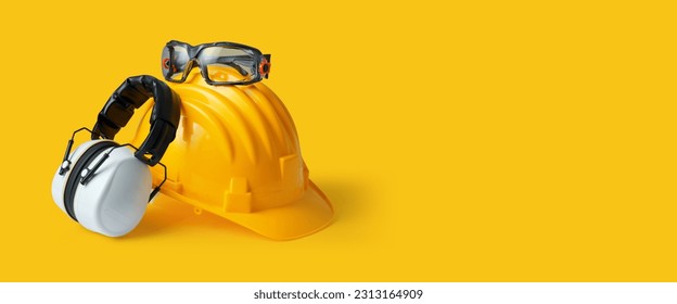 Safety helmet, ear muffs and goggles: personal protective equipment and workplace safety concept - Shutterstock ID 2313164909