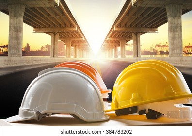 safety helmet on civil engineering working table against bridge construction in urban scene