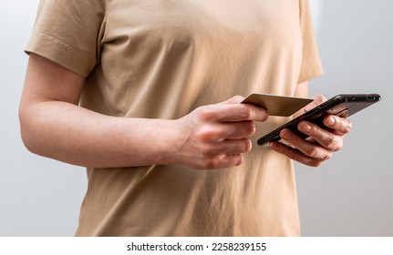 Safety of internet payment. Female hands closeup paying with bank debit card and mobile phone, smartphone application, tranfer cashless money, entering bankcard information, data. High quality photo - Shutterstock ID 2258239155