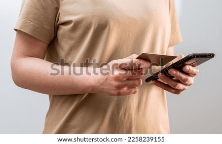 Safety of internet payment. Female hands closeup paying with bank debit card and mobile phone, smartphone application, tranfer cashless money, entering bankcard information, data. High quality photo