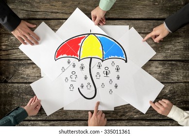 Safety and life insurance concept - six hands assembling a colourful umbrella sheltering many people icons drawn on white papers. - Powered by Shutterstock