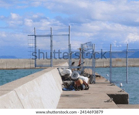 A safety measure at the end of the breakwater of the fishing port
located on the coast of the Inland Sea of Japan.
Beyond the fence is the red lighthouse installed to mark the entrance to the port.
