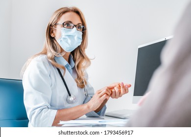 Safety Medicine. Female Doctor In Medical Mask Talking With Senior Patient In Office