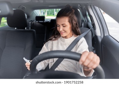 safety and people concept - happy smiling young woman or female driver with smartphone driving car in city