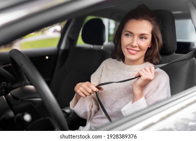 Safety And People Concept - Happy Smiling Young Woman Or Female Car Driver Fastening Seat Belt