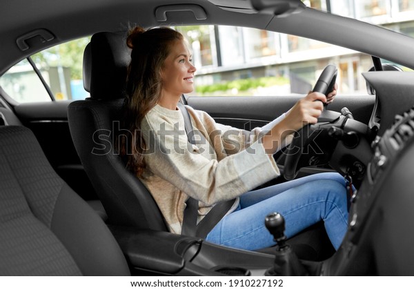 safety and people concept - happy\
smiling young woman or female driver driving car in\
city