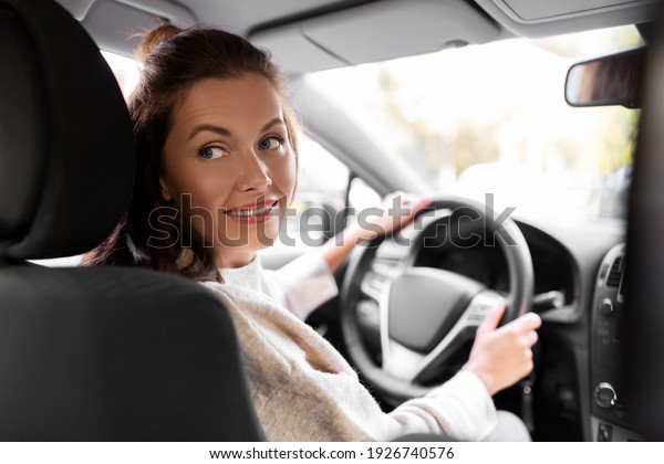 safety and people concept - happy\
smiling young woman or female driver driving car in\
city