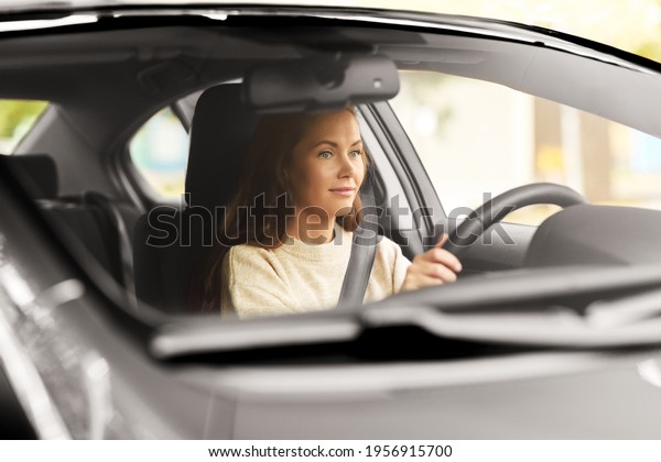 safety and people concept - young woman or female\
driver driving car in\
city
