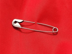 Safety Pin Attached To Red Shirt Background