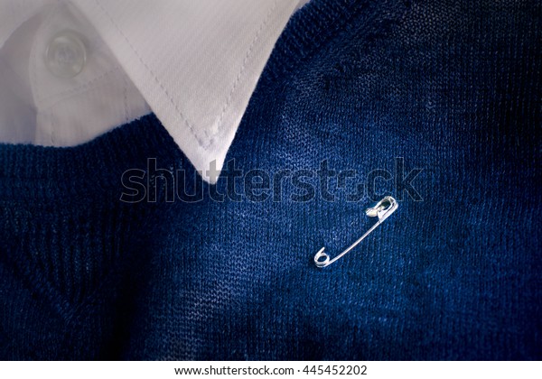Safety pin clasp on clothing or shirt. For safety\
pin campaign that encouraging the British public and show\
solidarity after Brexit (UK or EU referendum result). Safety pin\
symbolic or Safety pin\
sign