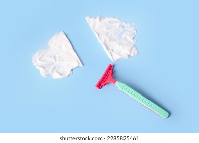 Safety razor and shaving foam on color background