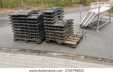 Safety and securing of a construction site: view of delivered traffic barriers and delineator posts with base plates, ready for installation, selective focus, extra copy space un the foreground