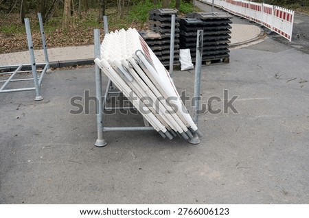 Safety and securing of a construction site: view of delivered traffic barriers and delineator posts with base plates, ready for installation, selective focus, extra copy space un the foreground