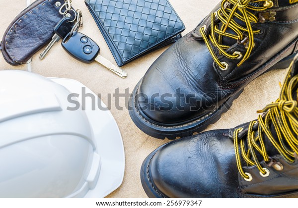 safety shoe and safety helmet,wallet,car Key\
on Brown Background