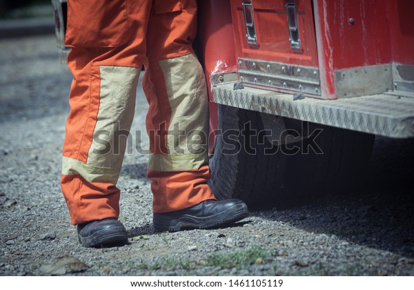 Safety shoes for Firefighter and\
safety suite stand near fire engine car, fire safety\
concept