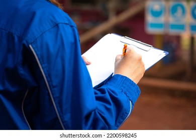 A safety supervisor or manager is writing down on paper for taking note during safety audit at the operation work site. Industrial safety working action scene, close-up and selective focus. - Powered by Shutterstock