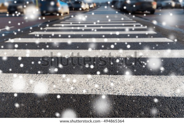safety, traffic laws, highway code and road sign\
concept - close up of pedestrian crosswalk on city car parking over\
snow