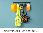 Safety vest, hardhat and tools hanging on blue wall