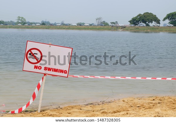 The safety warning sign\
with red character. No swimming for warning human do not swim in\
the natural pool . The area has dangerously strong with risk of\
drowning.