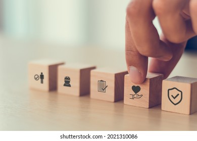 Safety at work concept. Hand holds cubes wooden block with safety icons; safety first, protections, health, regulations and insurance.  Used for banner, beautiful bright background and copy space. - Shutterstock ID 2021310086
